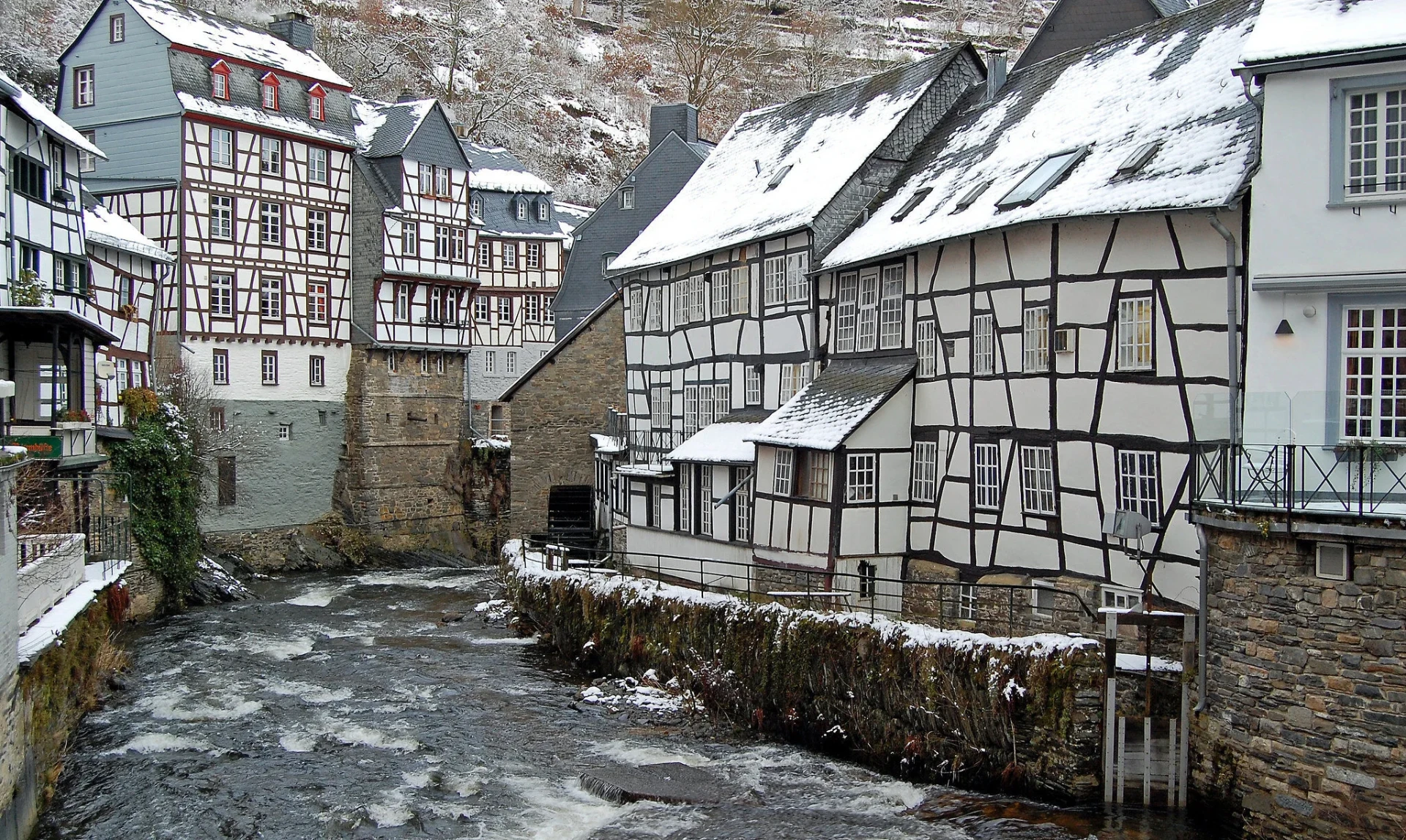 Half-timbered houses along a frozen river in a snowy European town